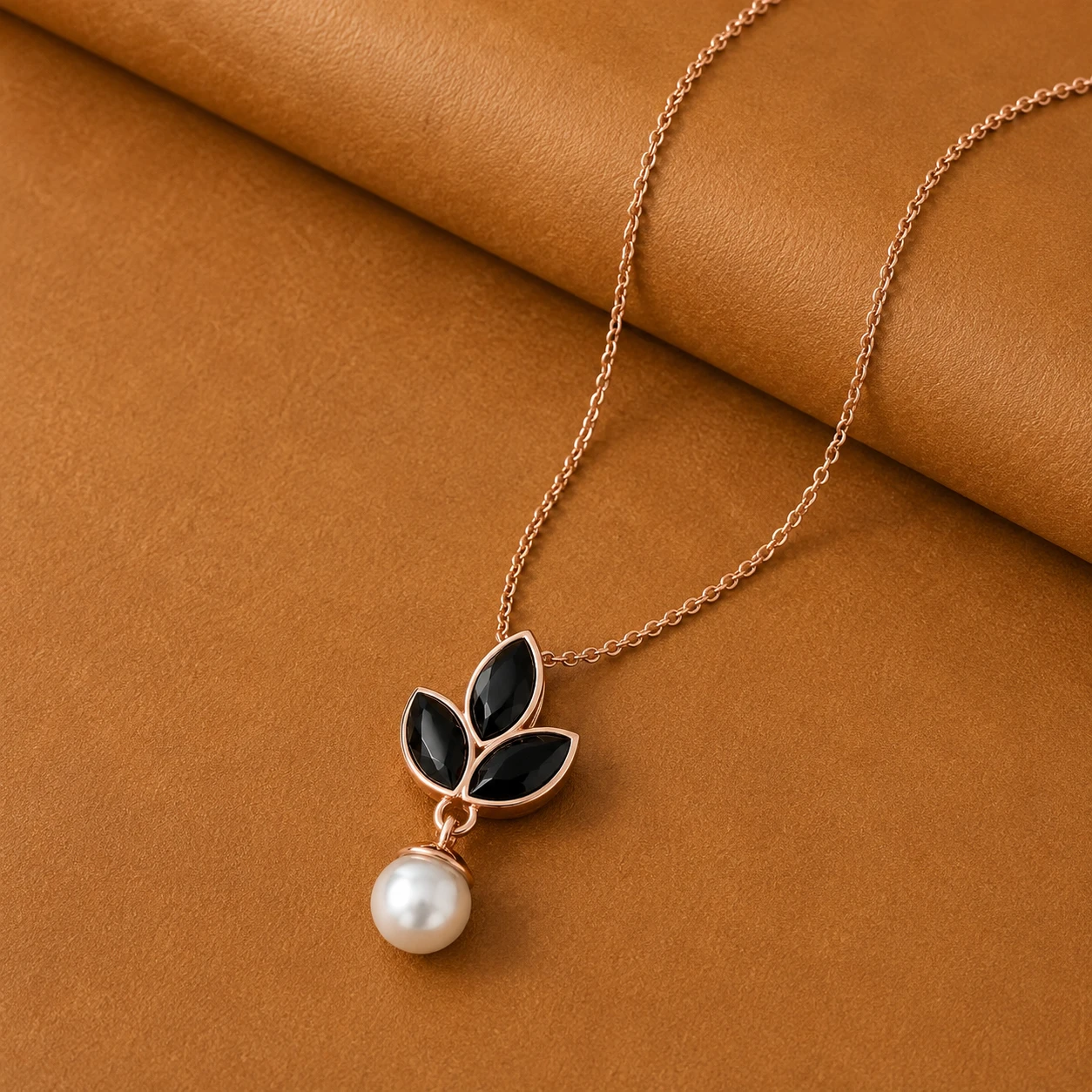 Three black marquise cut diamonds arranged as leaves above a white freshwater pearl drop pendant in rose gold plating.
