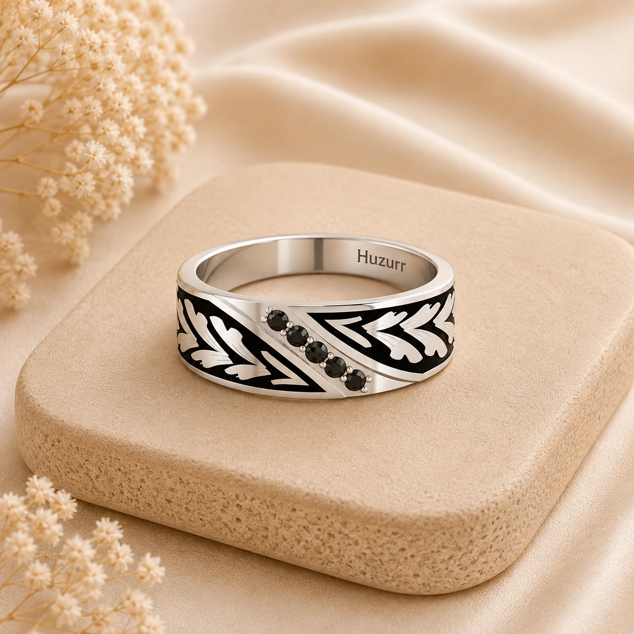 Thick silver wedding band featuring five round black diamonds with engraved leaf patterns and black enamel