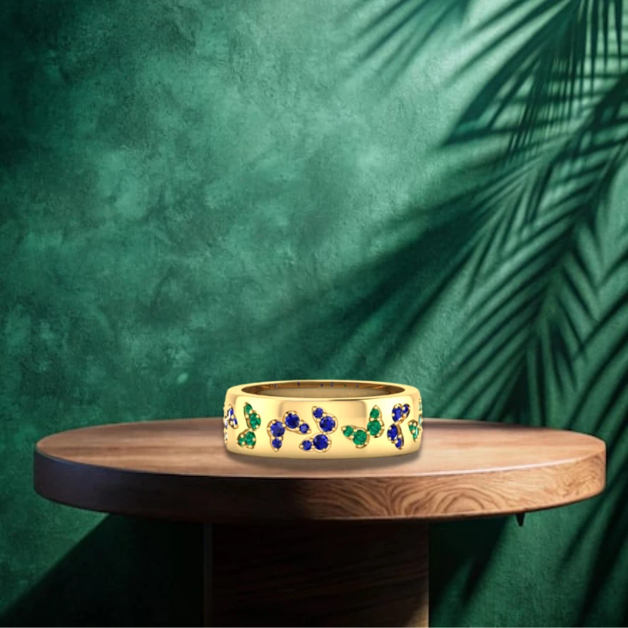 Blue sapphire and green emerald pave butterflies encircle a wide gold plated band ring