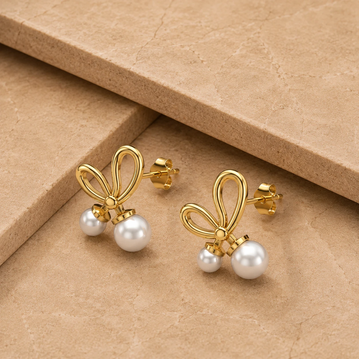 Bow style gold-plated stud earrings with twin white freshwater pearls