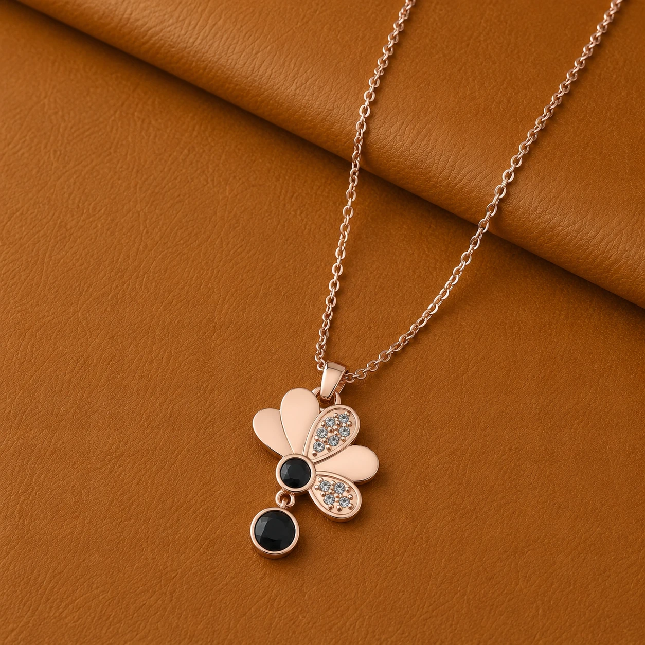 Rose gold plated half flower pendant with two round black diamonds and diamond paved petals.