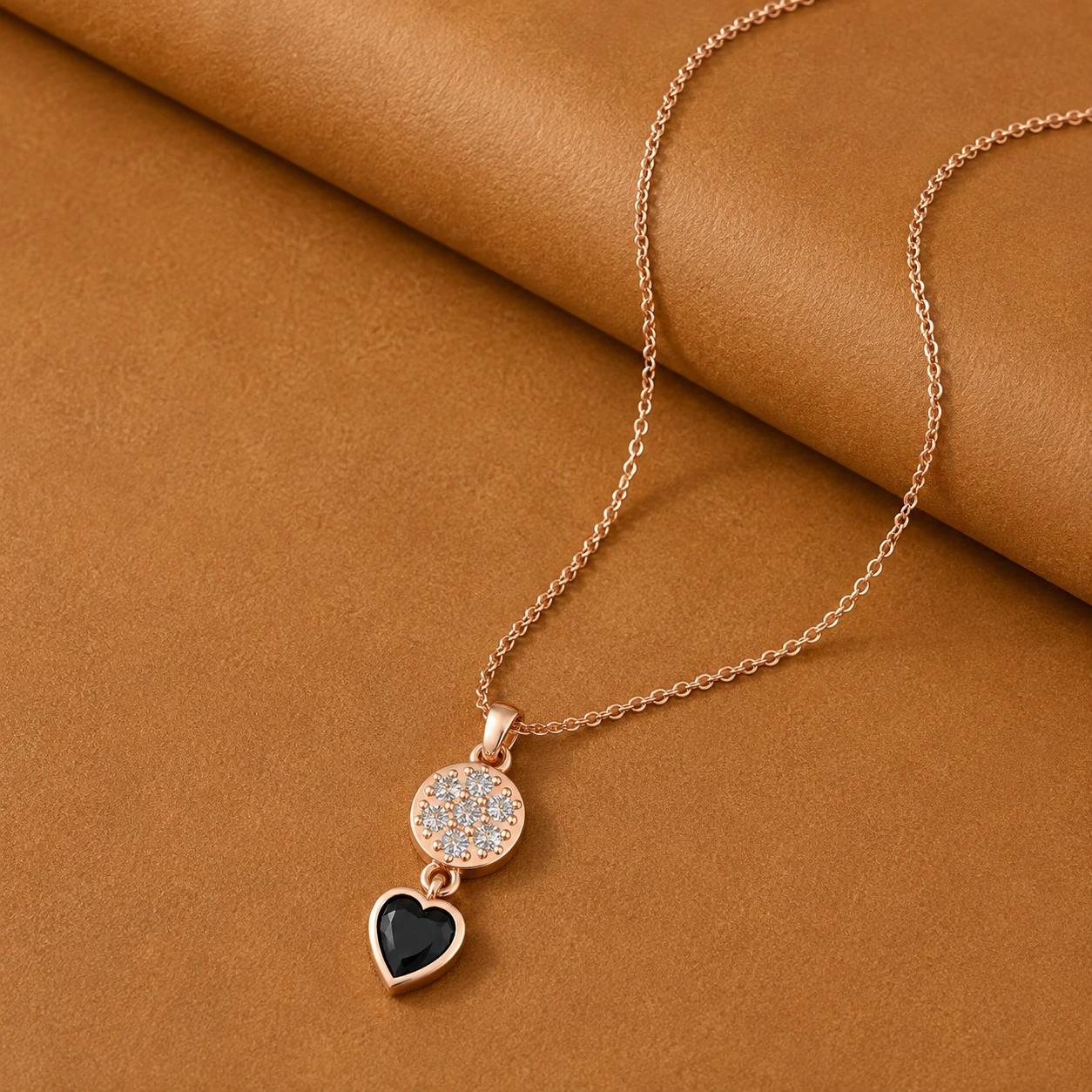 Heart shaped black diamond drop pendant hanging from a circular pave diamond cluster in rose gold plating.