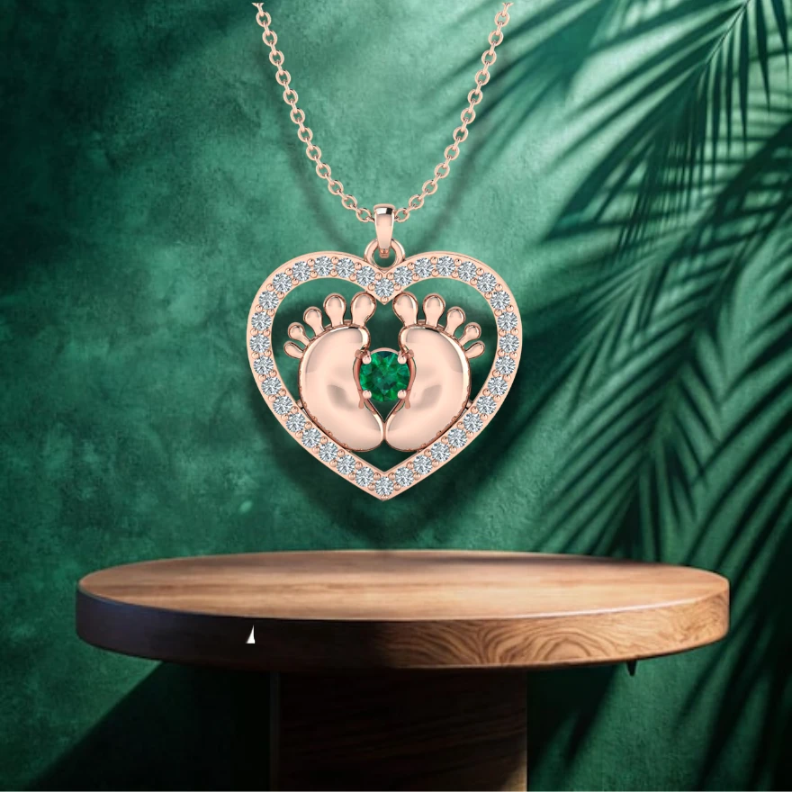 Rose gold plated heart pendant showing small baby footprints, diamonds, and a green emerald