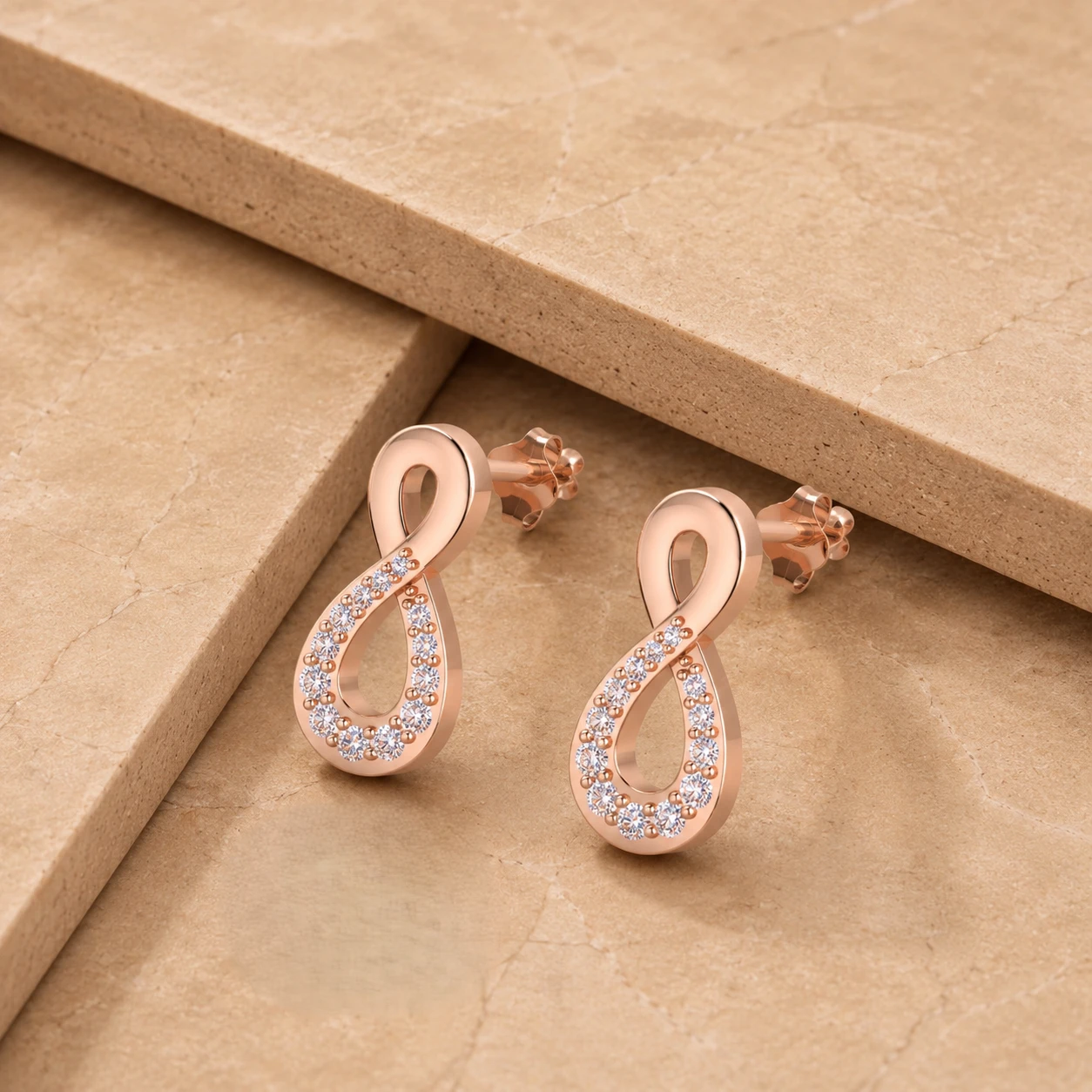Infinity symbol post earrings plated in rose gold and micro paved with shimmering diamonds