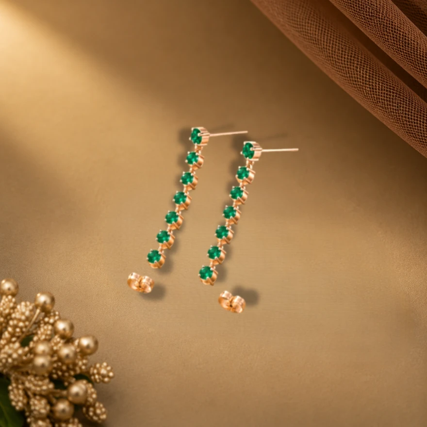 Long linear dangle earrings crafted with a vertical row of round lab-emeralds set in a delicate gold-plated chain strand