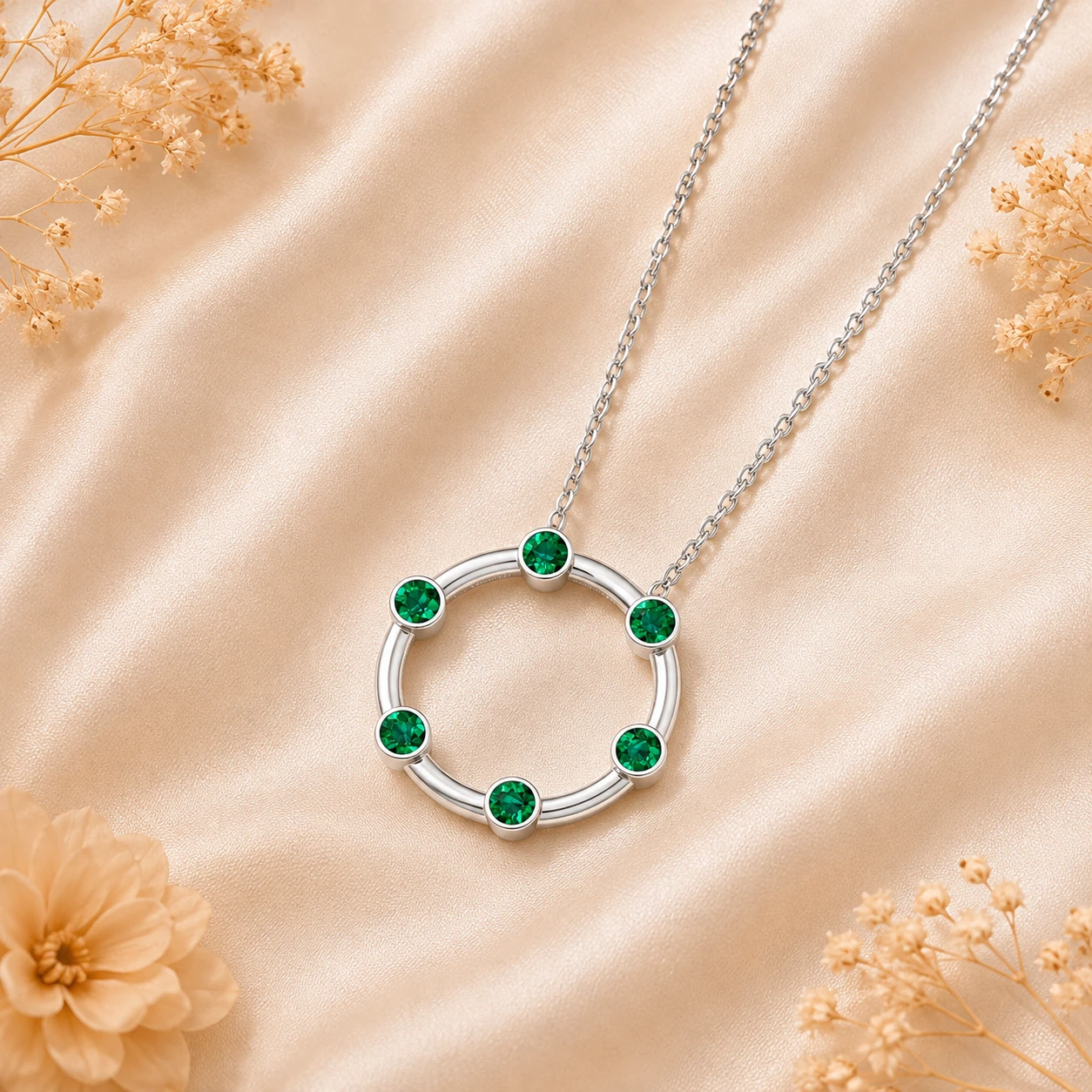 Open circle eternity pendant decorated with small bezel set vibrant green emeralds