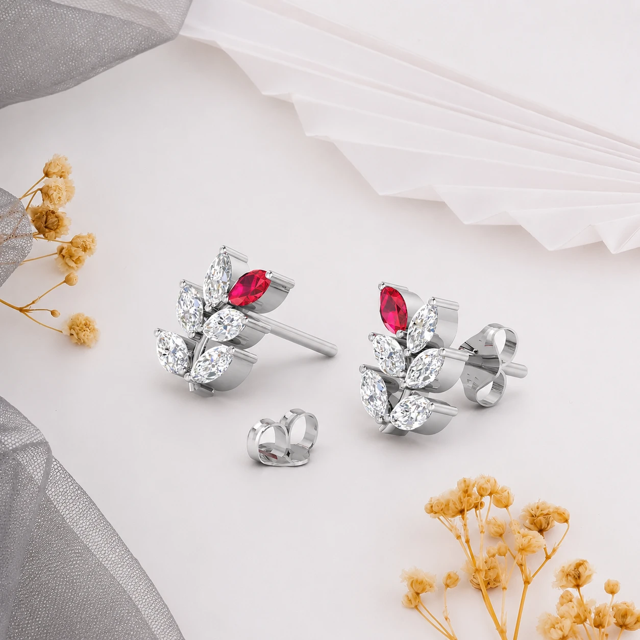 Marquise diamonds and a single pink ruby creating a leaf branch on these silver studs